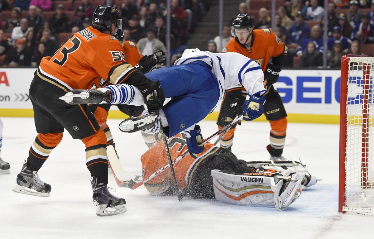 Maple Leafs center Nazem Kadri, top center, goes airborne as he tries to score on Ducks goalie John Gibson, below, while under pressure from defensemen Shea Theodore, left, and Josh Manson during the first period.