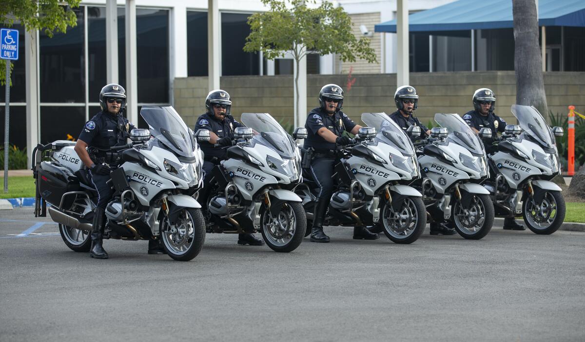 Costa Mesa Police Department motor officers line up across the street from protesters on Tuesday.