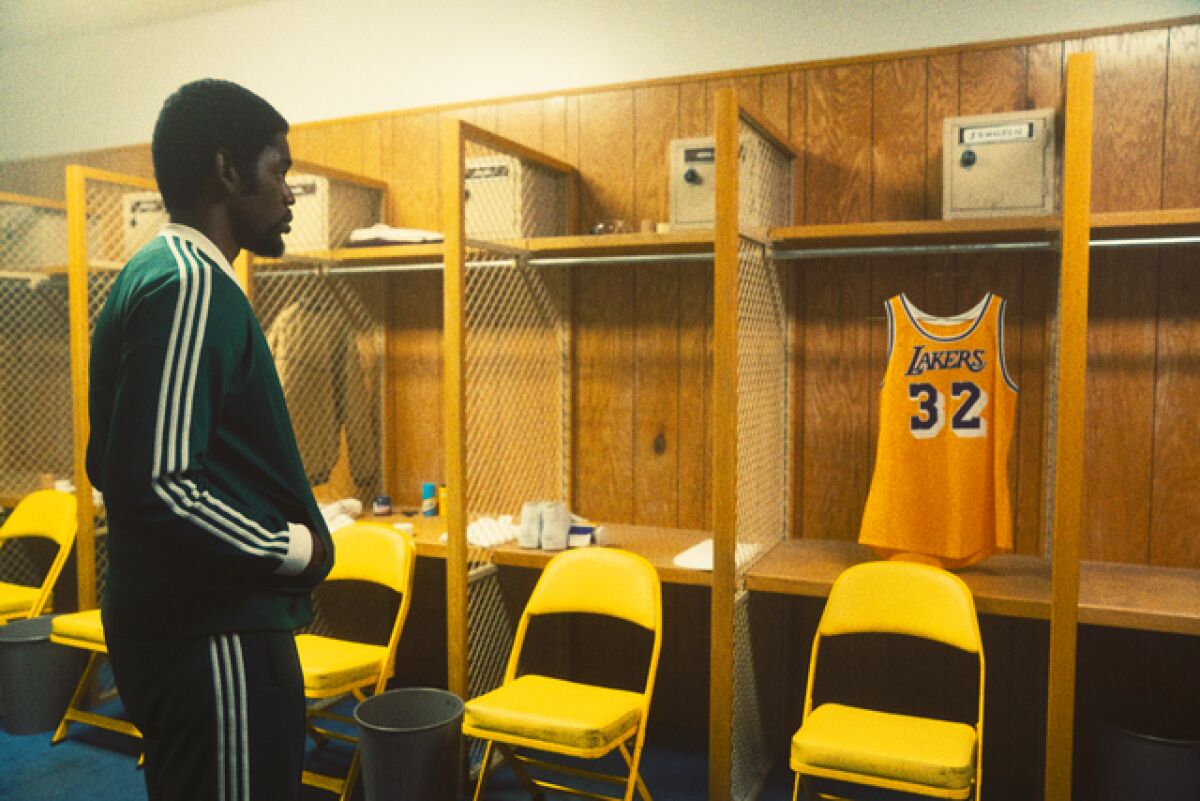 A man looks at a Lakers jersey in a locker room