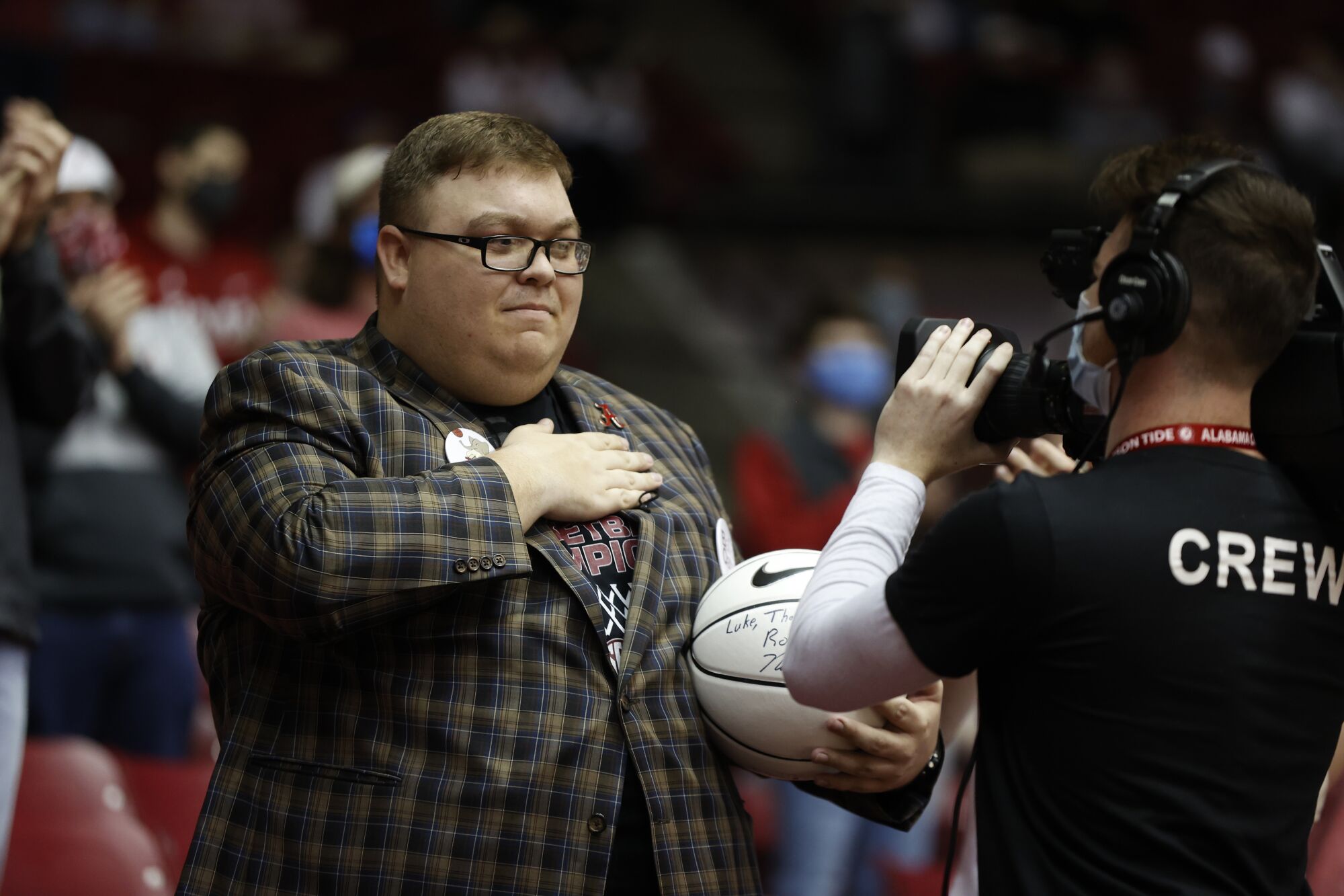 Alabama superfan Luke Ratliff holds a hand over his heart as he receives a signed basketball.