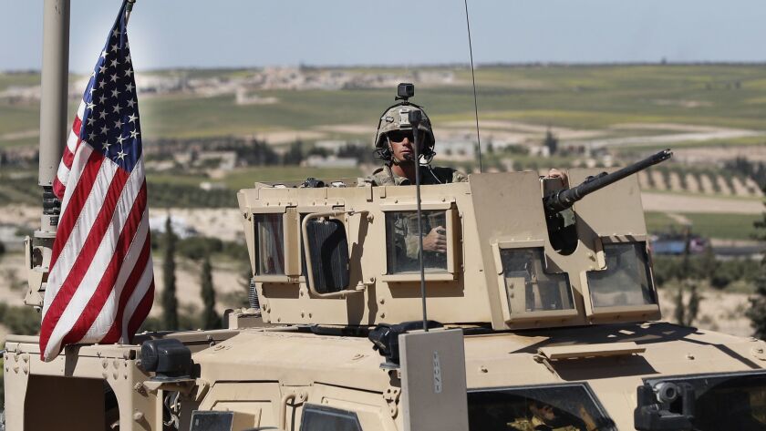 A U.S. soldier sits in an armored vehicle on a road leading to the front line in northern Syria on April 4.