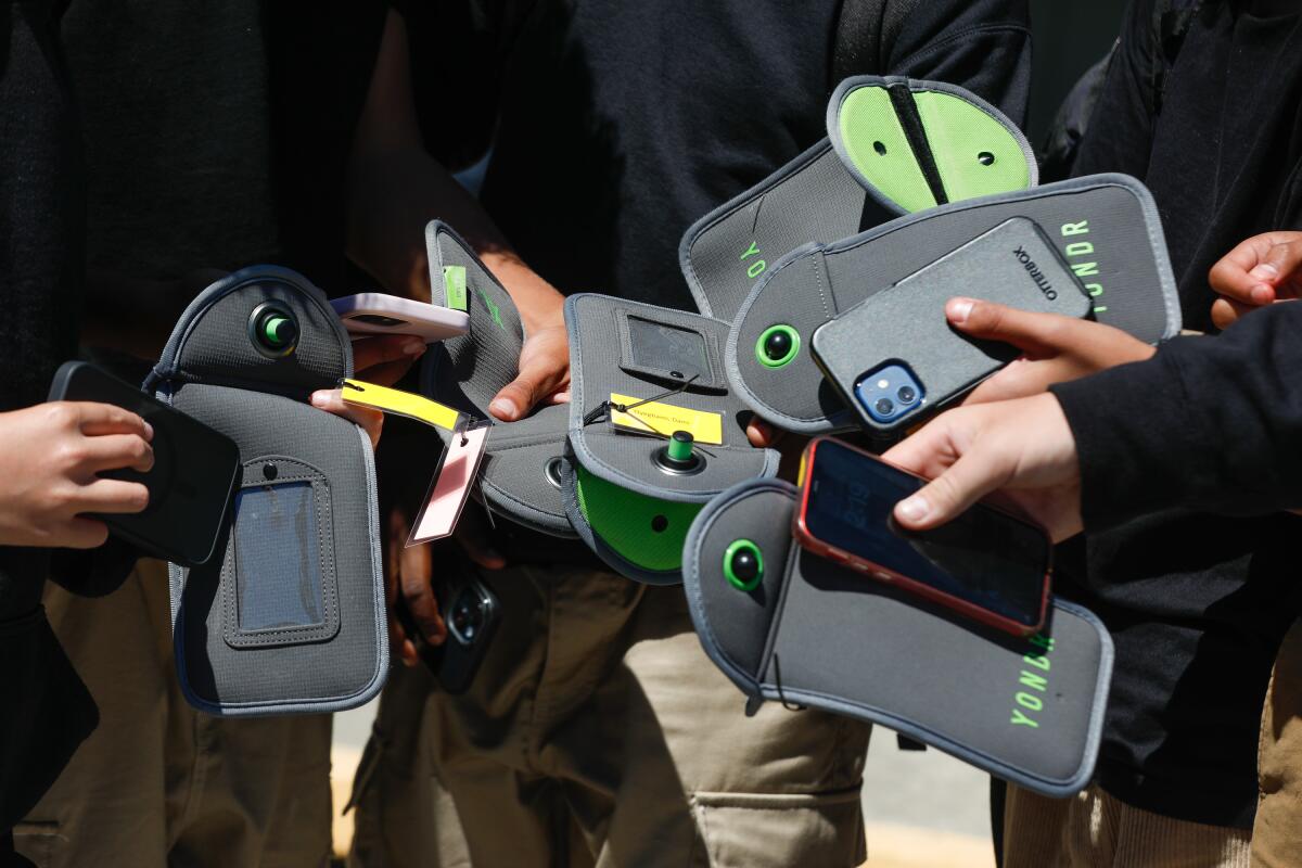 Several pairs of hand hold phones and pouches.