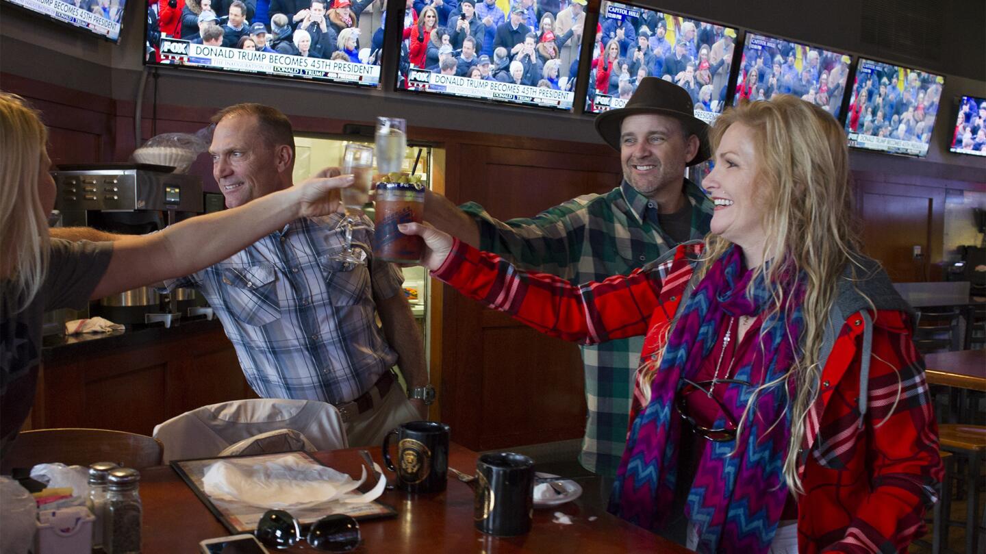 Dave Clarke, Dan Byers and K.C. Emery, from left, celebrate after Donald Trump’s swearing-in as the 45th president of the United States as they gather with other supporters Friday morning at Rudy’s Pub and Grill in Newport Beach.