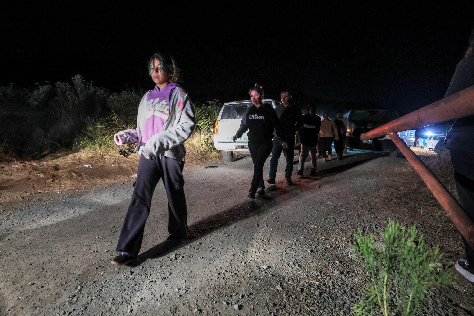 A man shines a flashlight on a line people sitting on the ground.