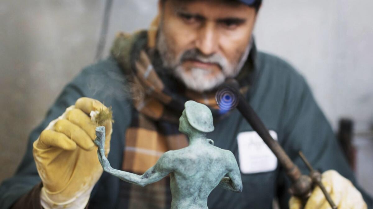 Ricardo Godinez applies the patina to the solid bronze statuette.