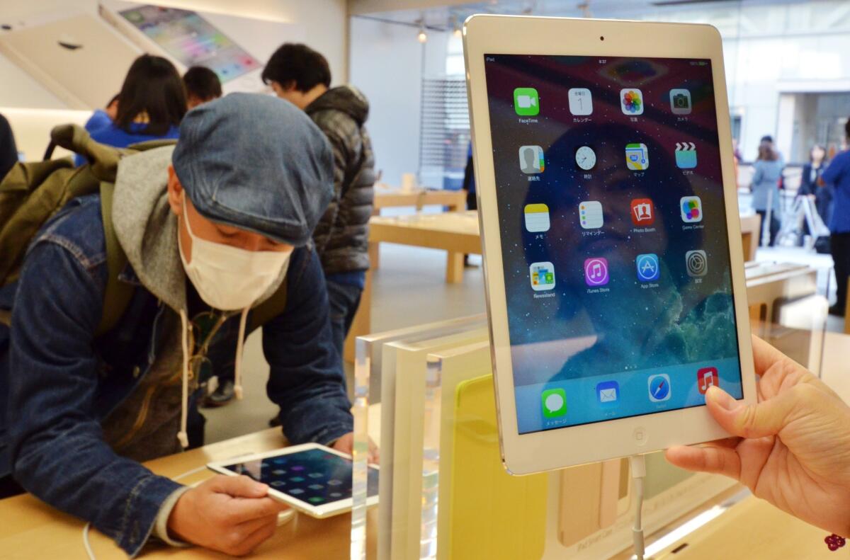 Customers check out iPad Air tablets at an Apple store in Tokyo.