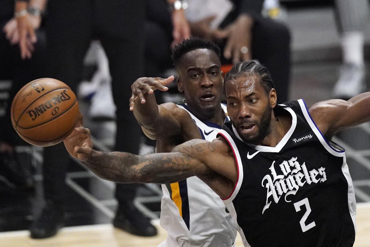 Clippers forward Kawhi Leonard passes the ball while under pressure from Utah Jazz guard Miye Oni.