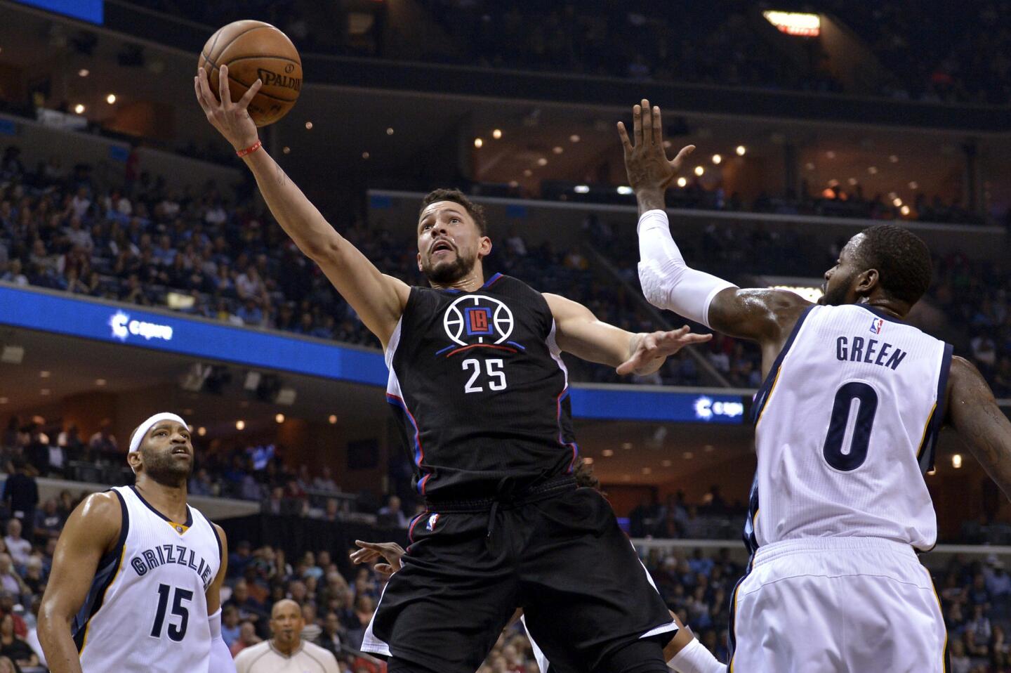 Clippers guard Austin Rivers (25) splits the defense of Grizzlies forward JaMychal Green (0) and guard Vince Carter (15) for a layup during the first half.