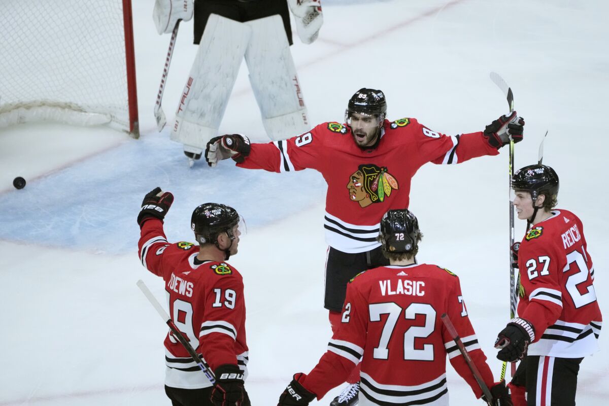 Chicago Blackhawks' Andreas Athanasiou (89) celebrates his goal against the New Jersey Devils off an assist from Jonathan Toews (19) with Toews, Alex Vlasic (72) and Lukas Reichel during the third period of an NHL hockey game Saturday, April 1, 2023, in Chicago. The Devils won 6-3. (AP Photo/Charles Rex Arbogast)