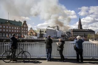 La gente toma fotografías mientras los bomberos apagan un incendio en el antiguo edificio de la Bolsa de Valores de Copenhague, Dinamarca, el martes 16 de abril de 2024. (Mads Claus Rasmussen/Ritzau Scanpix)