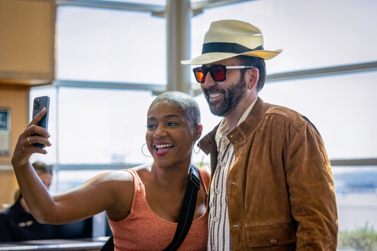 A man in a fedora poses with a woman taking a selfie.