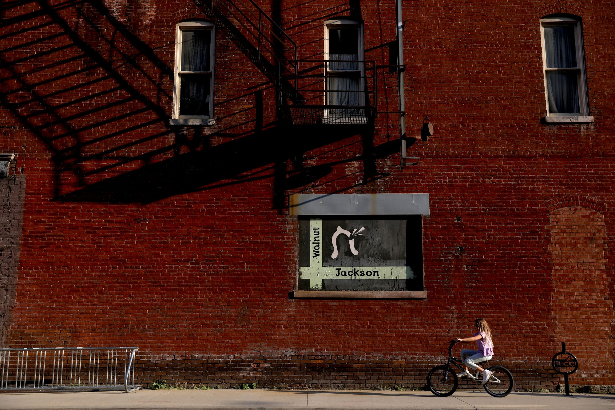 A young girl rides her bike along a street. in downtown Muncie, Ind.