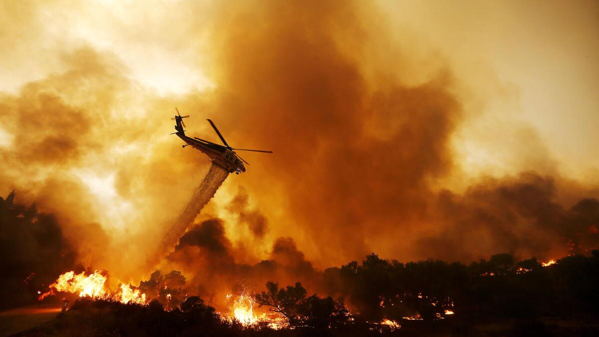 A firefighting helicopter drops water on the Sand fire as it burns out of control along Soledad Canyon Road near Acton.