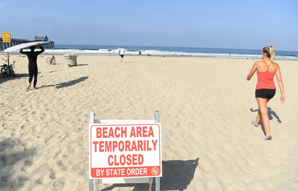 People walk along the sand in Newport Beach in defiance of a beach closure.