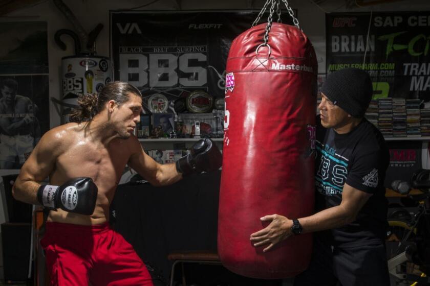 LOS ANGELES,CA --THURSDAY, FEBRUARY 22, 2018--Brian "T-City" Ortega, a UFC featherweight fighter, trains on the heavy bag, in the garage of his coach, James Luhrsen, right, in the Harbor City neighborhood of Los Angeles, CA, Feb. 22, 2018. The two met about 10 years ago in a south bay surf spot and have trained together since. Luhrsen says Ortega has a natural ability and he works to keep the recently-turned 27-year-old focused. Ortega's next fight is March 3, against Frankie Edgar, at UFC 222. (Jay L. Clendenin / Los Angeles Times)
