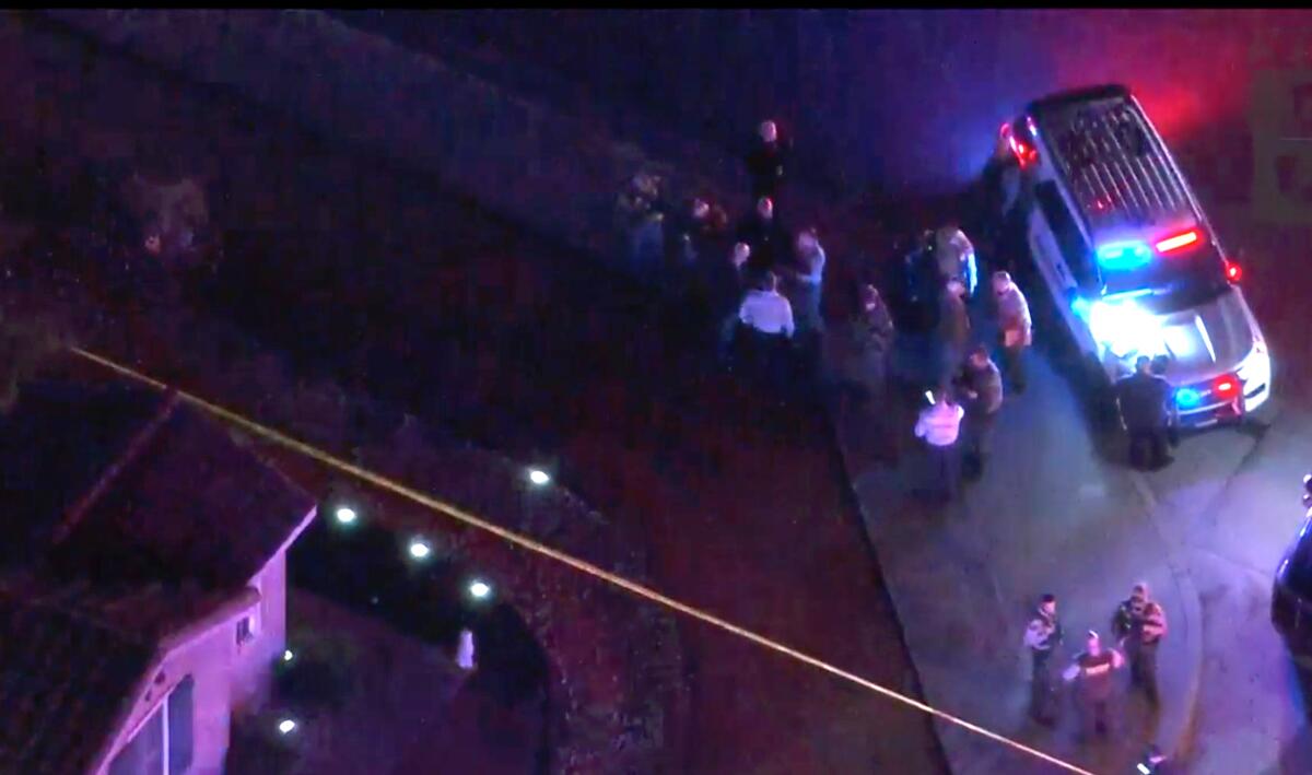 Aerial view of law enforcement officers outside a house with crime scene tape
