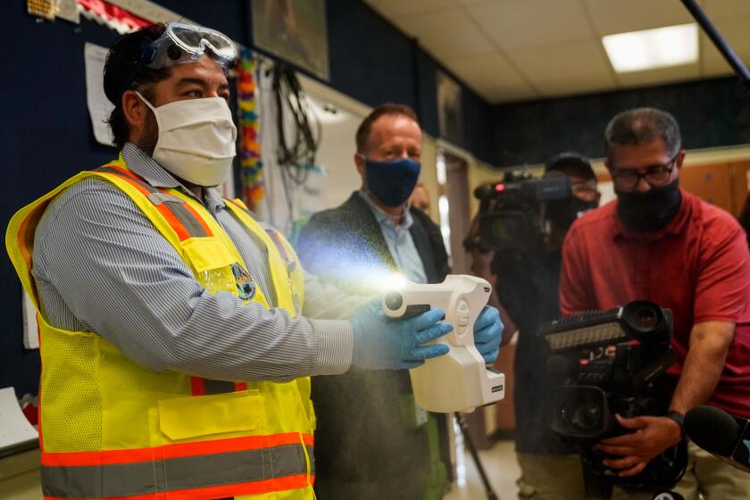 LAUSD staff member Adrian Pacheco demonstrates the use of sanitizing tools at Burbank Middle School. 