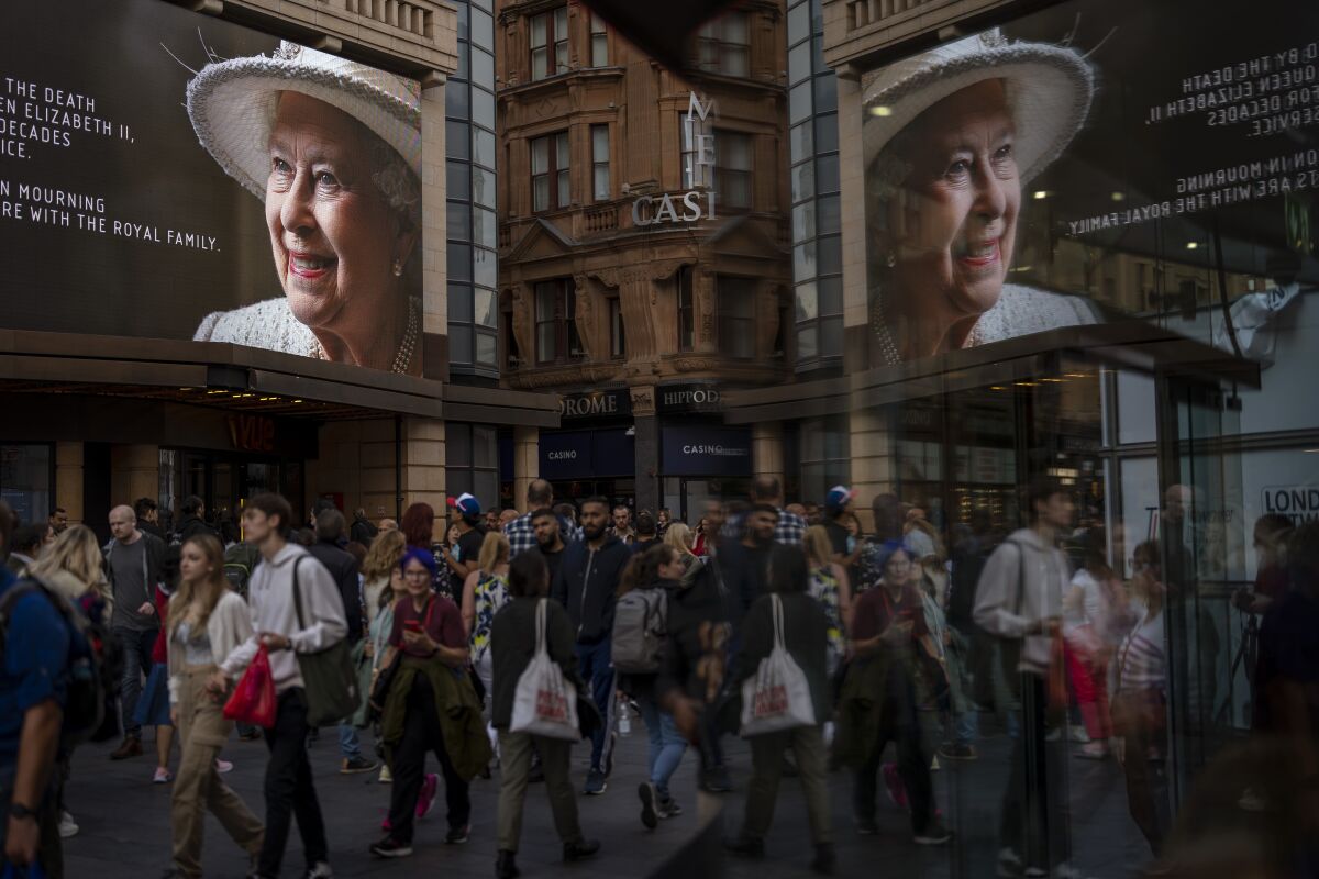 Peatones pasan frente a una valla publicitaria con una foto de la reina Isabel II en el centro de Londres