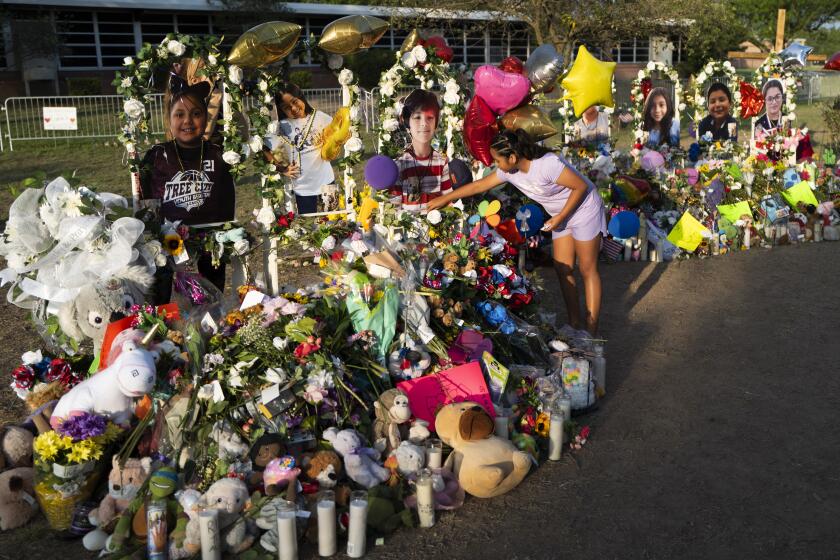 Aaliyah Banda, 11, places a bracelet in front of Uziyah Garcia's photo, one of the victims killed in last week's school shooting, at a memorial at Robb Elementary School in Uvalde, Texas, Tuesday, May 31, 2022. (AP Photo/Jae C. Hong)