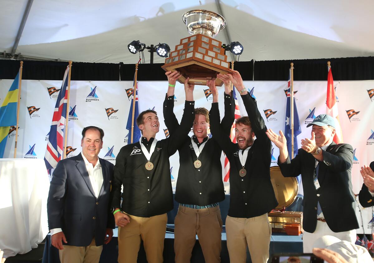 Alastair Gifford, skipper Nick Egnot-Johnson, and Sam Barnett, from the Royal New Zealand Yacht Squadron, hoist the Governor's Cup trophy during a celebration at the Balboa Yacht Club in Newport Beach on Saturday.