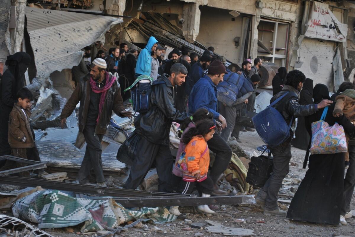 Syrian civilians walk as they are evacuated during a humanitarian operation in the besieged Old City of Homs.