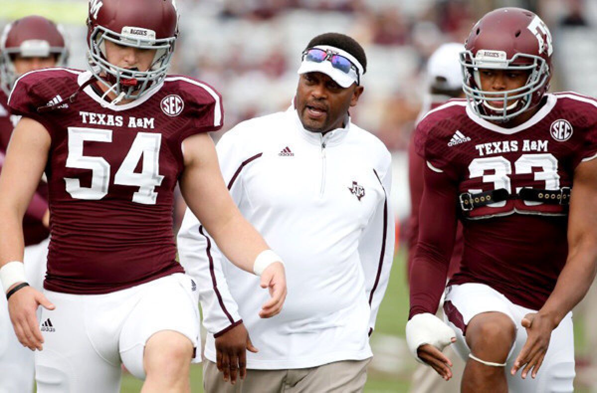 Texas A&M; Coach Kevin Sumlin talks to two of his players as they warm up for a game.