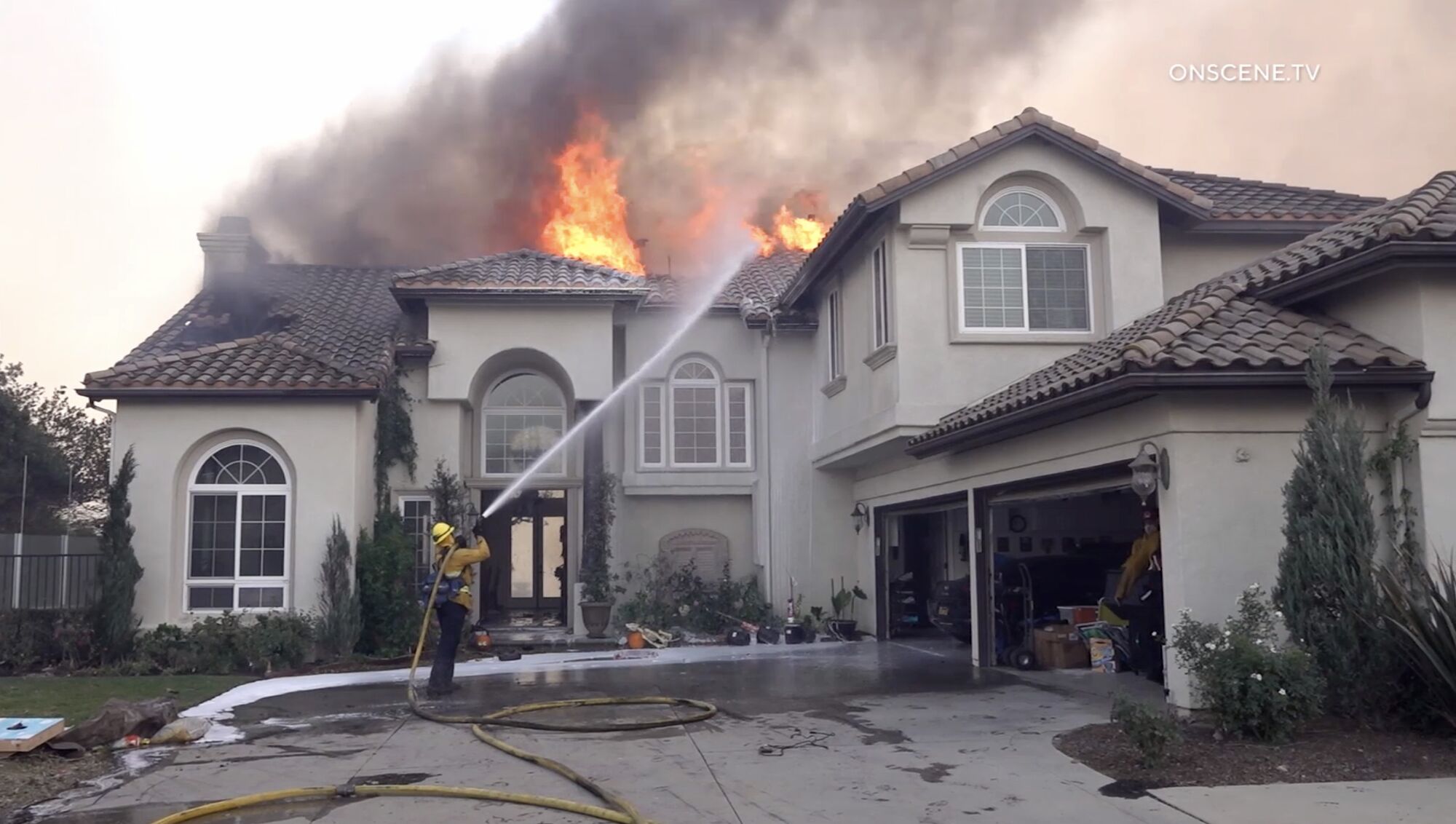 A firefighter hoses down a home fire in Yorba Linda that was sparked Monday by the Blue Ridge fire.