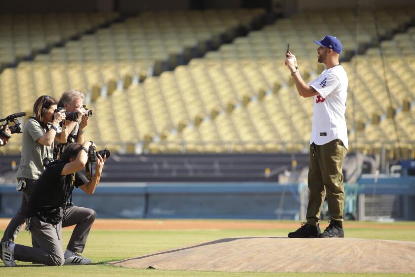 LOS ANGELES-CA-FEBRUARY 12, 2020: David Price, right, is joined by photographers on the field after a press conference officially introducing Price and teammate Mookie Betts as the newest Dodgers at Dodger Stadium on February 12, 2020. (Christina House / Los Angeles Times)