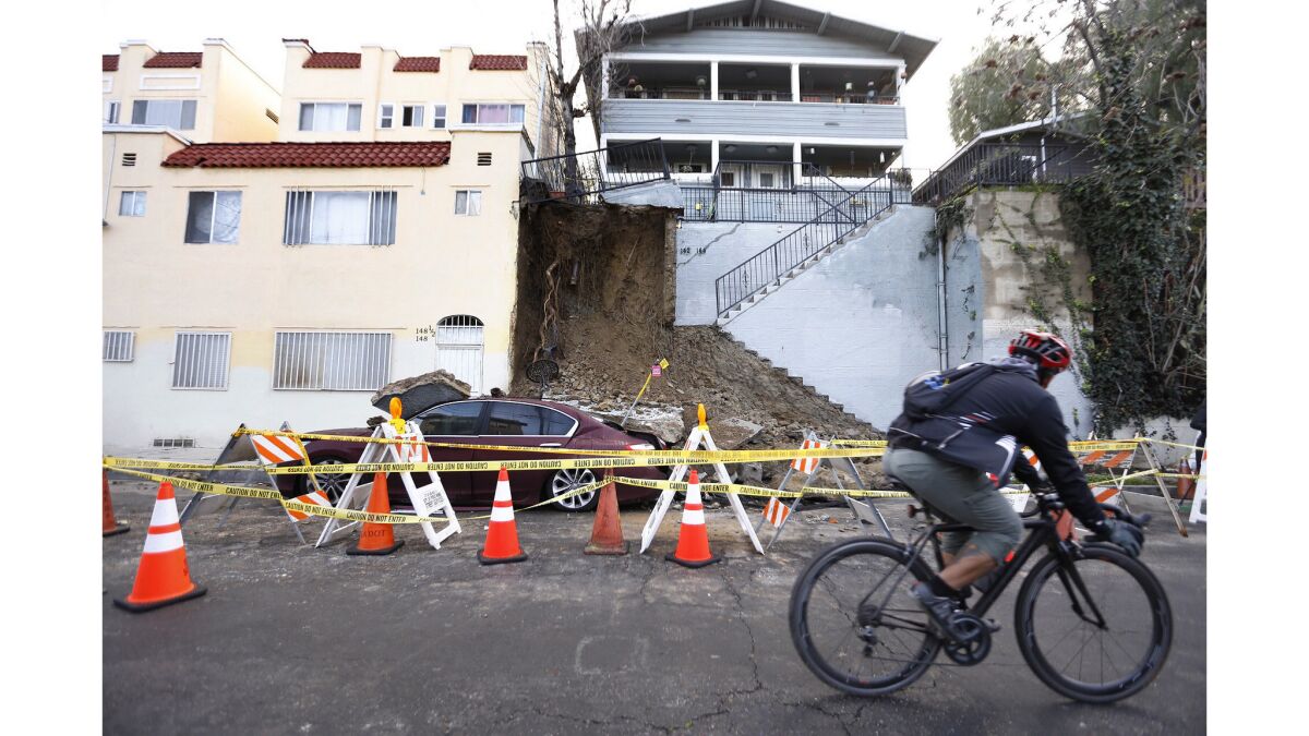 A car is partially buried by soil and concrete after rain collapsed a staircase in Echo Park.