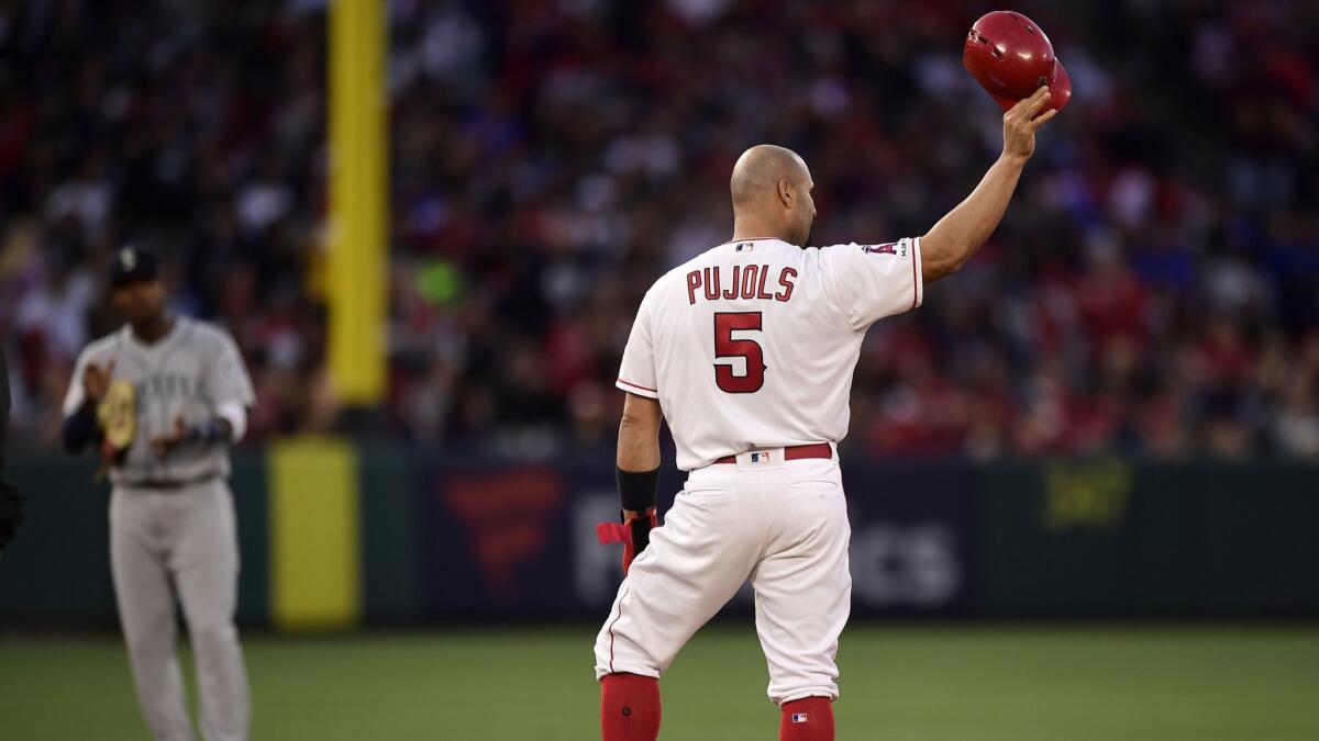 Albert Pujols tips his helmet to fans after hitting an RBI double as Seattle Mariners shortstop Tim Beckham claps during the third inning. Pujols tied Babe Ruth in career RBIs, then passed him with a homer in the ninth.