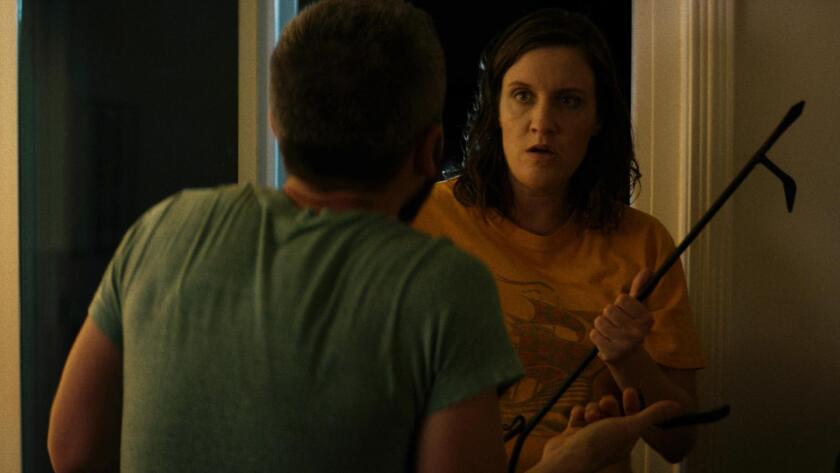 A woman holding a fire poker facing a man