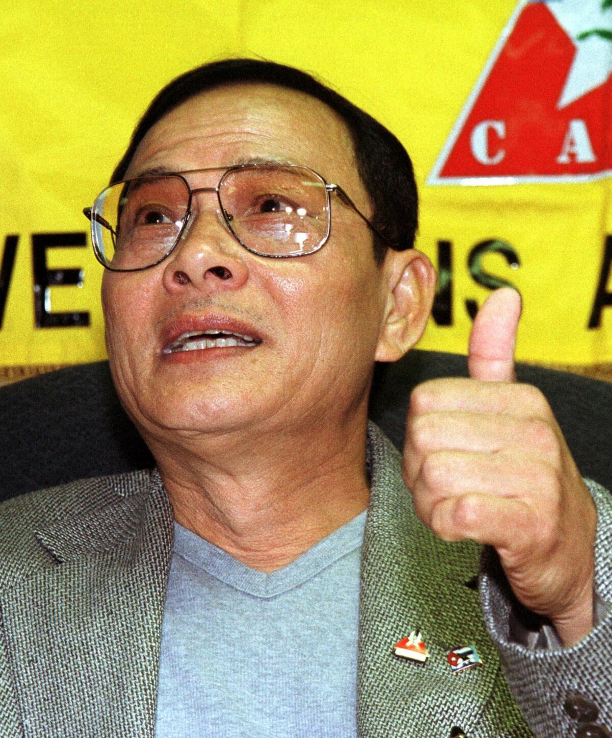 Pilot Ly Tong gestures as he responds to a reporter after receiving medals from the Brothers to the Rescue and the Cuban American Veterans Assn. in Miami in 2000.