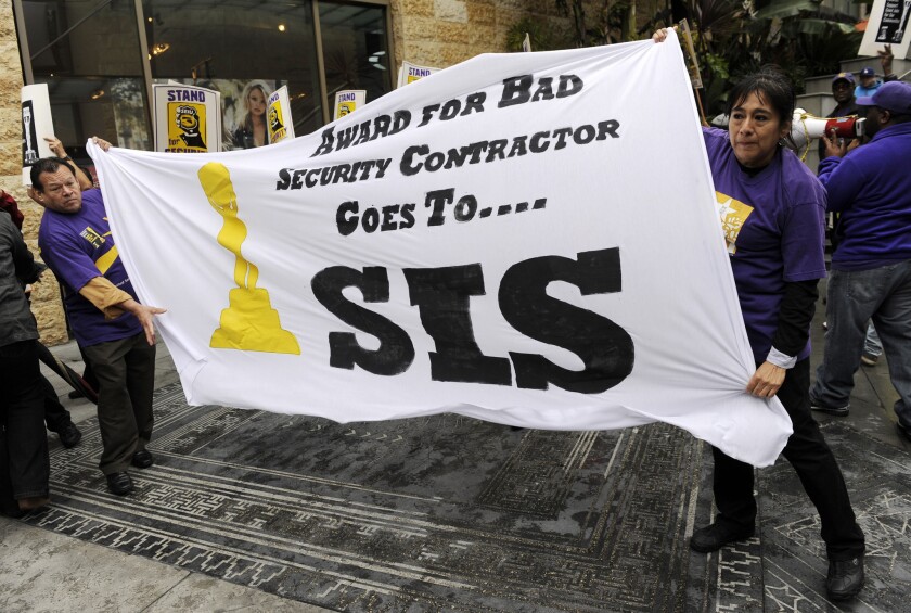 Protesters hold a banner criticizing the Academy of Motion Picture Arts and Sciences' use of the security firm Security Industry Specialists (SIS), in front of the Dolby Theatre, the site of Sunday's 86th Academy Award ceremony, on Friday, Feb. 28 in Los Angeles. Approximately 50 Los Angeles security officers urged the academy to use a unionized security contractor.
