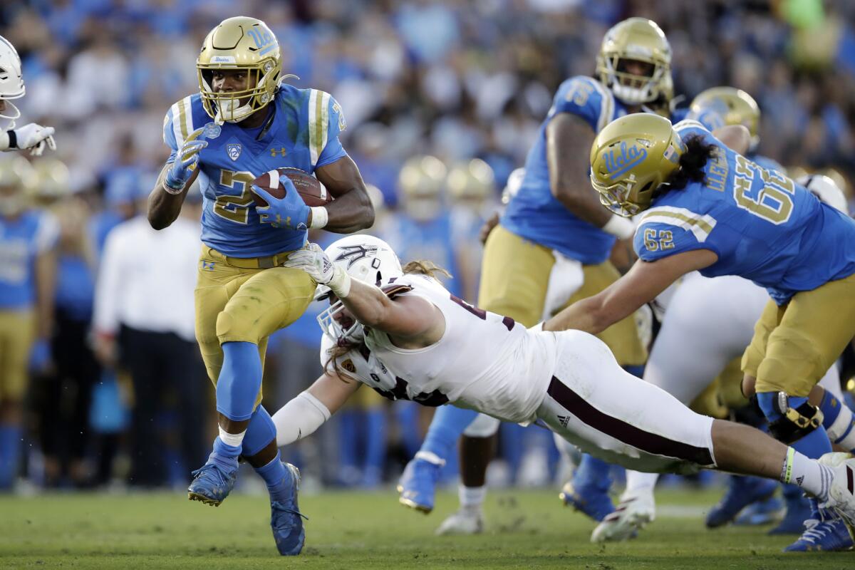 UCLA running back Joshua Kelley, left, runs for a touchdown past Arizona State defensive lineman Roe Wilkins during the first half on Oct. 26 at the Rose Bowl.