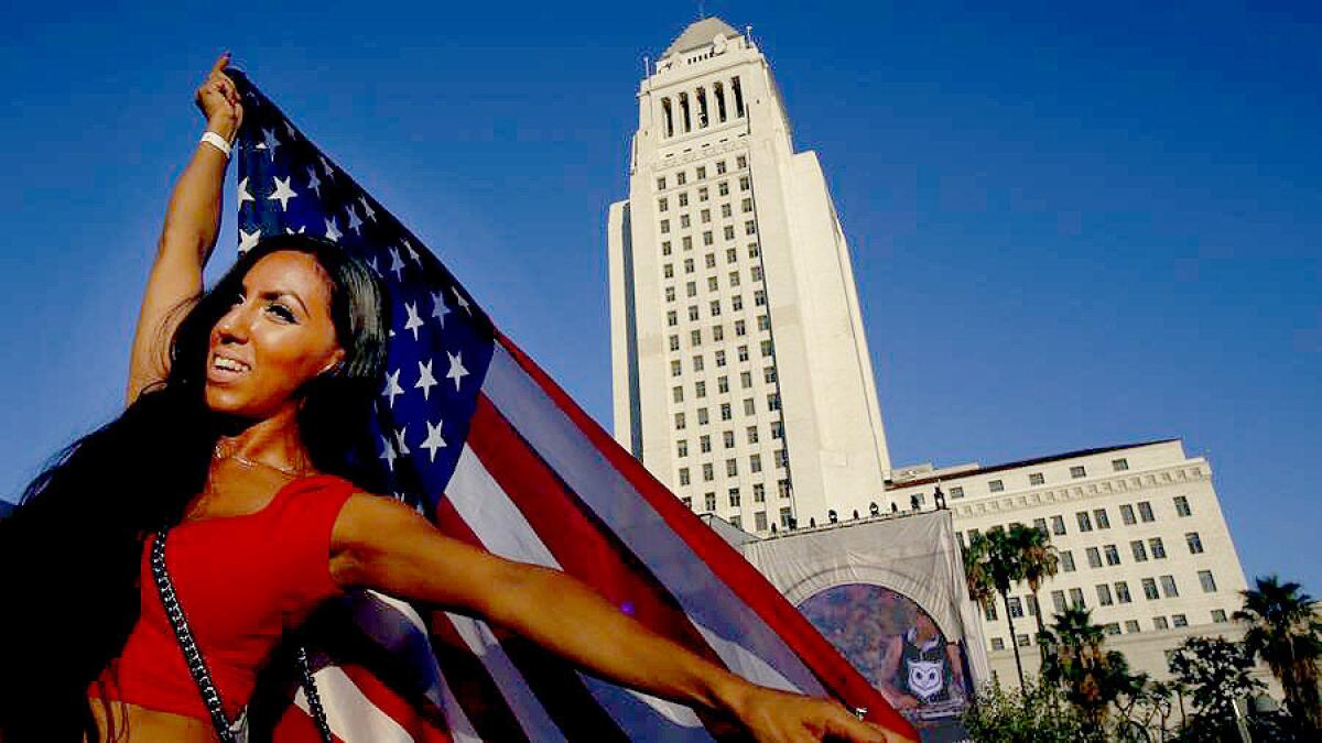 Maryel Ceballos, 29, of Los Angeles, holds up an American flag in front of City Hall.