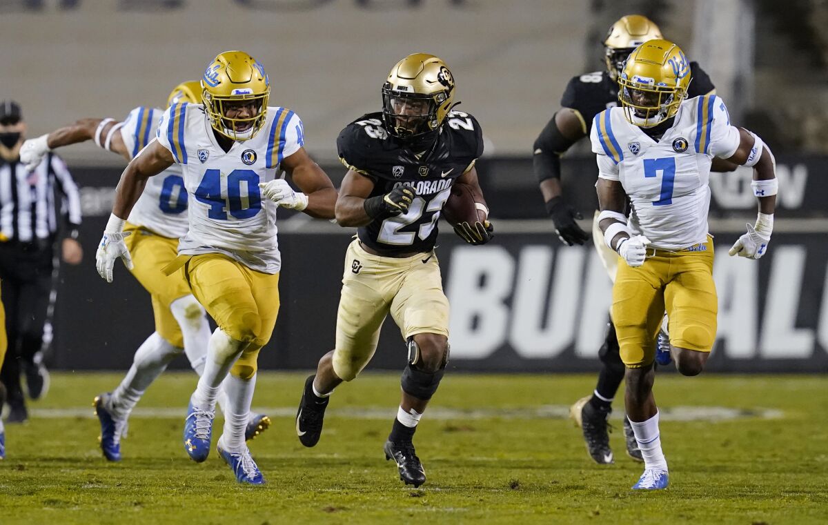 Colorado running back Jarek Broussard slips between UCLA linebacker Caleb Johnson and defensive back Mo Osling III.