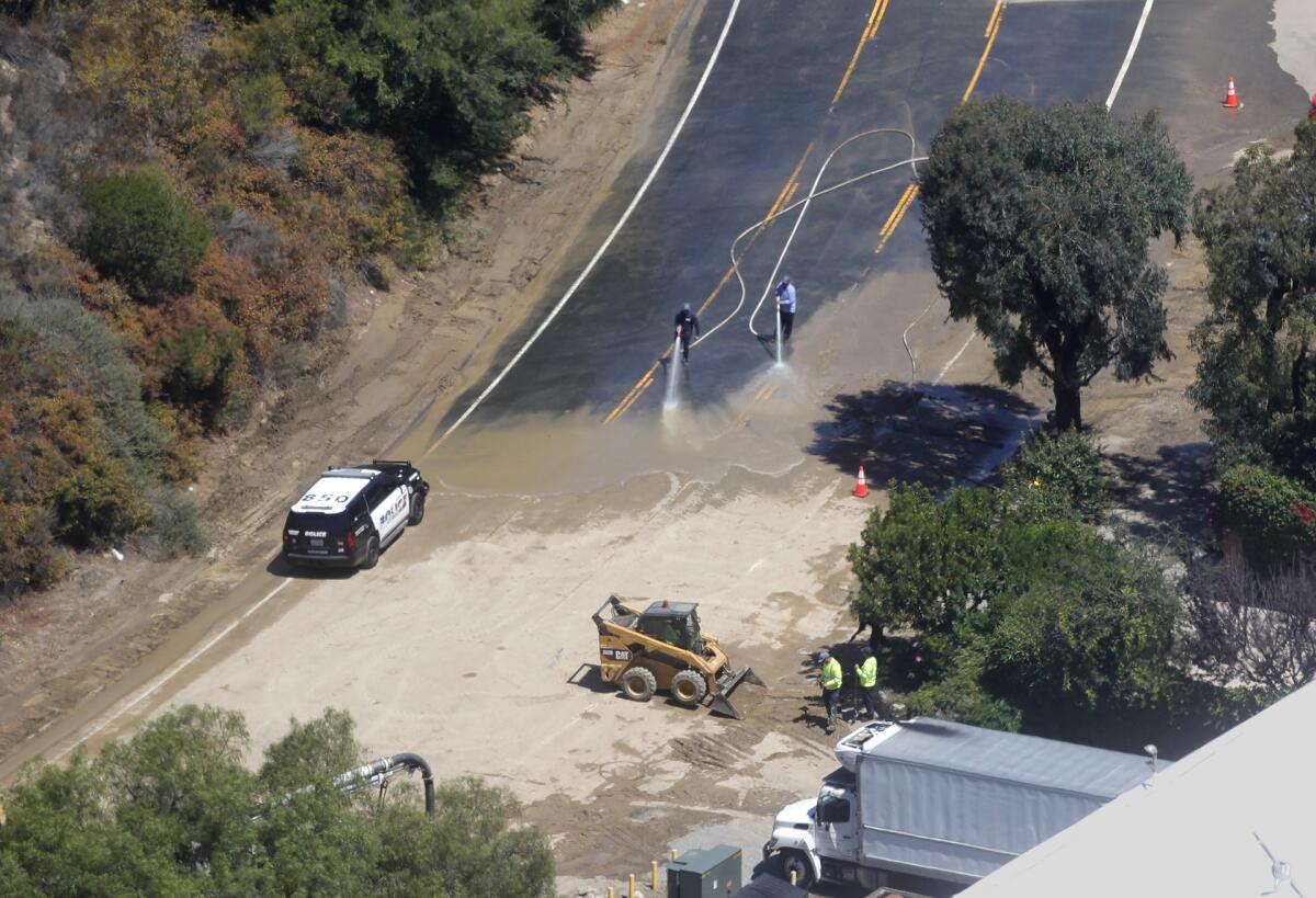 Laguna Beach Water District crews clear dirt and debris at the big bend in Laguna Canyon Road after a water main break.