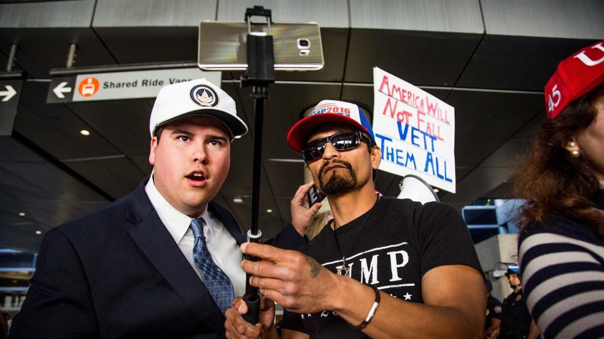 Trump supporters Omar Navarro, left, and Harim Uzziel live-stream their counter-protest at Los Angeles International Airport of the executive order by President Trump banning immigrants from seven majority-Muslim countries.