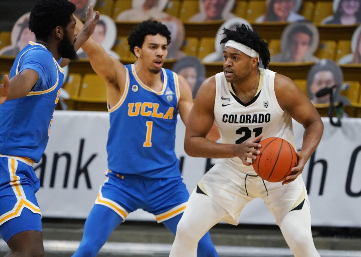 Colorado forward Evan Battey looks to pass in front of UCLA guard Jules Bernard and forward Cody Riley.