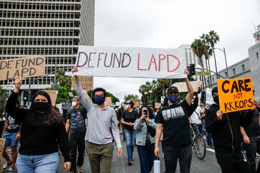 LOS ANGELES, CA - JUNE 05: A variety of signs, including "Defund LAPD," were held high, among about 1,000 people gathered to protest the death of George Floyd and in support of Black Lives Matter, in downtown, Los Angeles, CA, on Friday, June 5, 2020. (Jay L. Clendenin / Los Angeles Times)