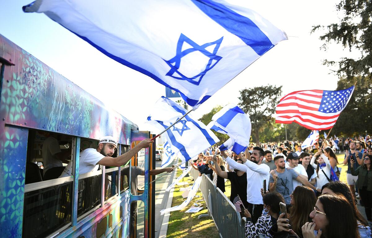 People wave Israeli flags and an American flag at a rally