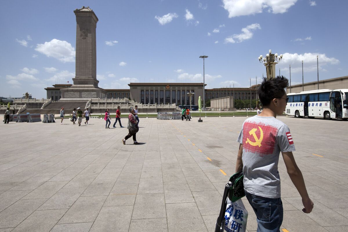 A tourist, right, wears a t-shirt displaying the logo of the Chinese Communist Party as he visits Tiananmen Square in Beijing last month.