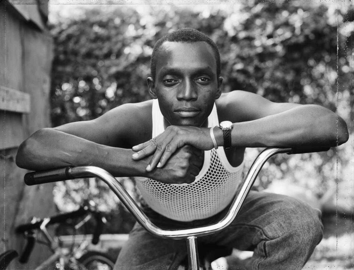 A young man resting on a bike.