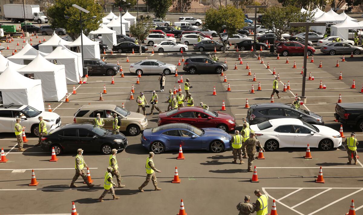 Cars line up between orange cones in a Cal State Los Angeles  parking lot