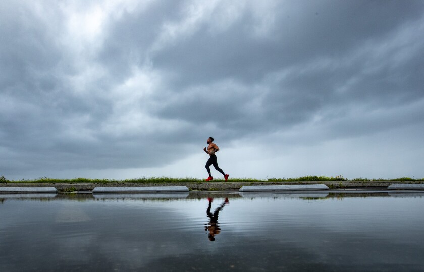 A jogger runs along the path at Will Rogers State Beach as storm clouds move onshore in Pacific Palisades earlier this month.