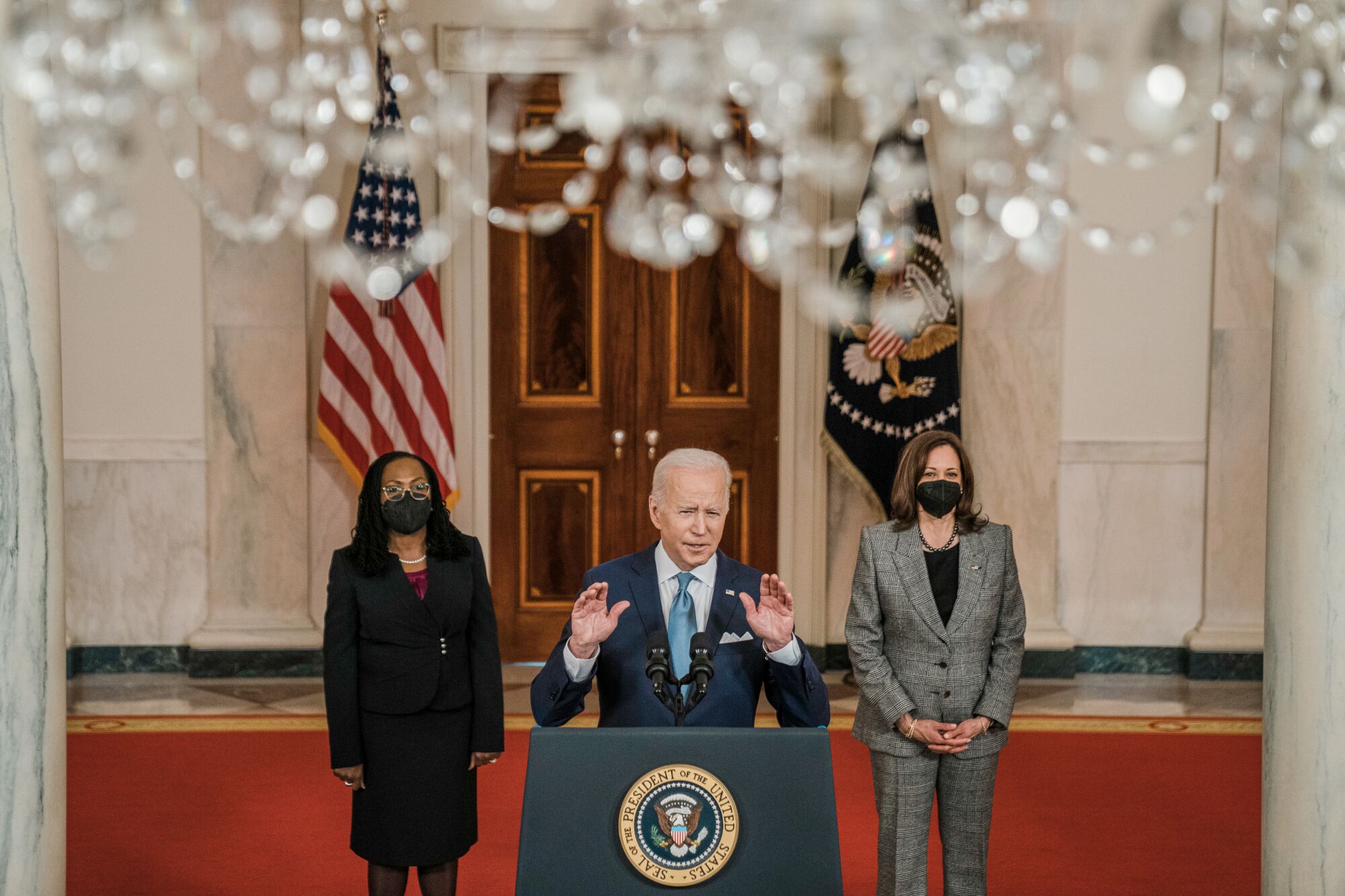 Joe Biden stands a lectern with Ketanji Brown Jackson and Kamala Harris behind him.