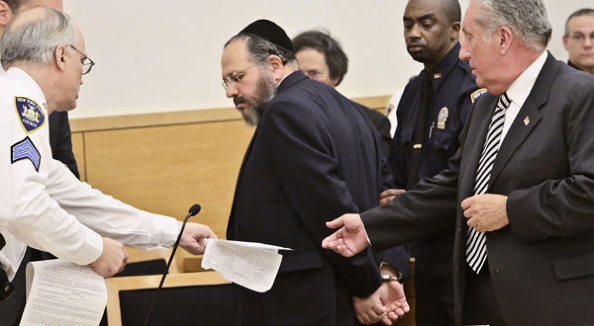 Nechemya Weberman, center, a religious counselor in a New York City ultra-Orthodox Jewish community, is lead away in handcuffs in Brooklyn Supreme Court.