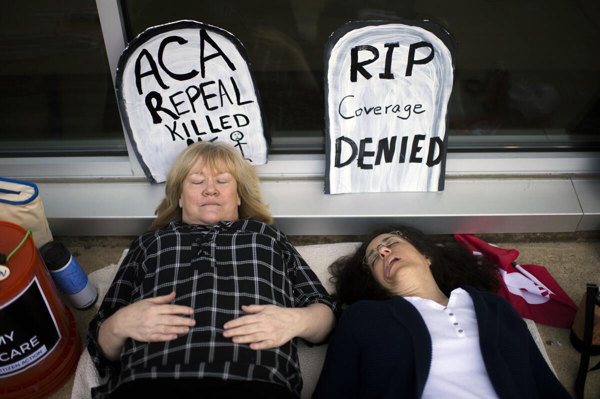 Maureen Quinn, left, and Maria Palmer pretend to be dead as protesters gather before a town hall held by New Jersey Republican Rep. Tom MacArthur in Willingboro, N.J., on May 10.