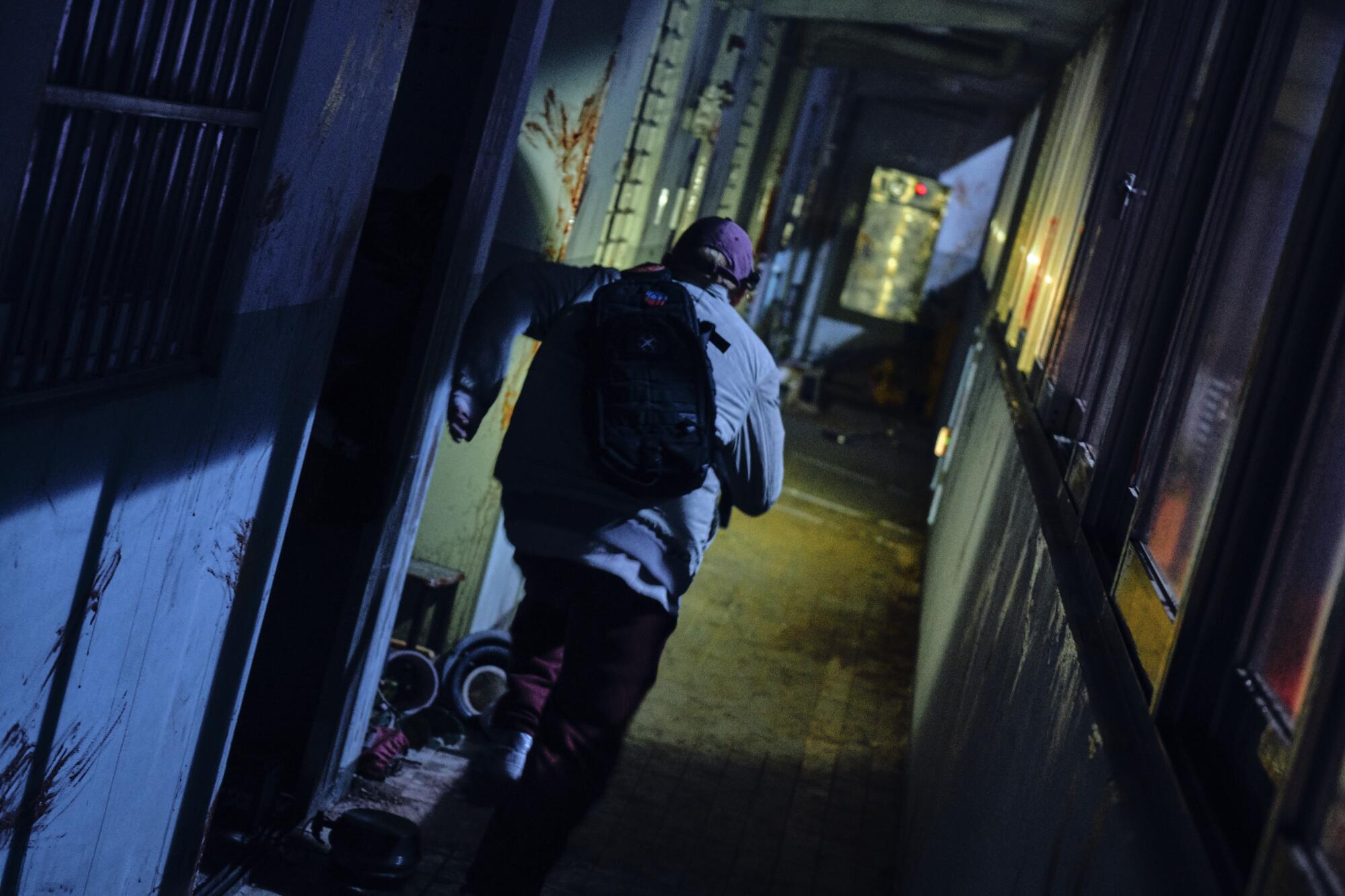 A person runs through a dark alleyway in a scene from the Netflix movie #Alive