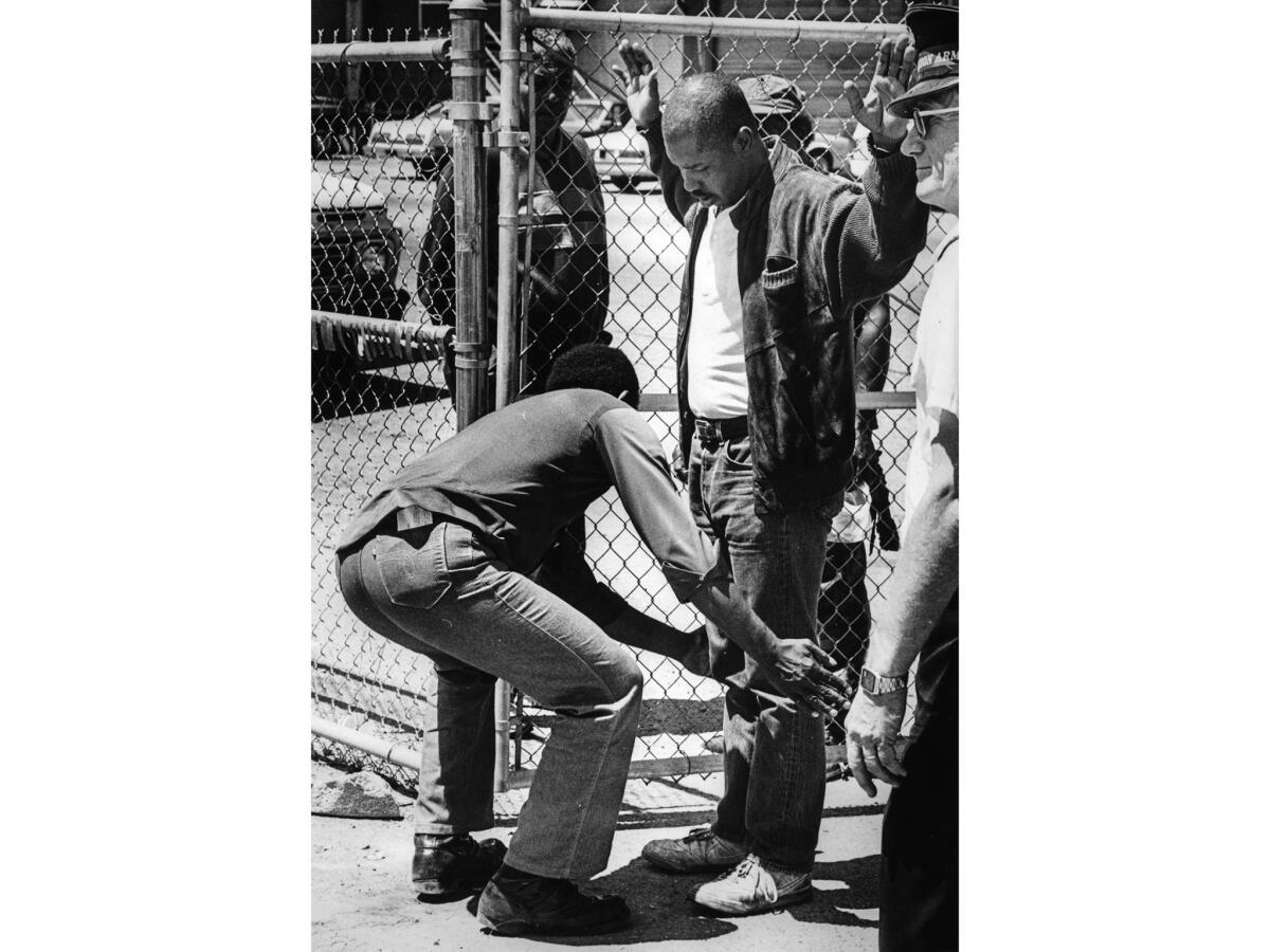 June 15, 1987: A man is searched for weapons and contraband at the entrance to the encampment.